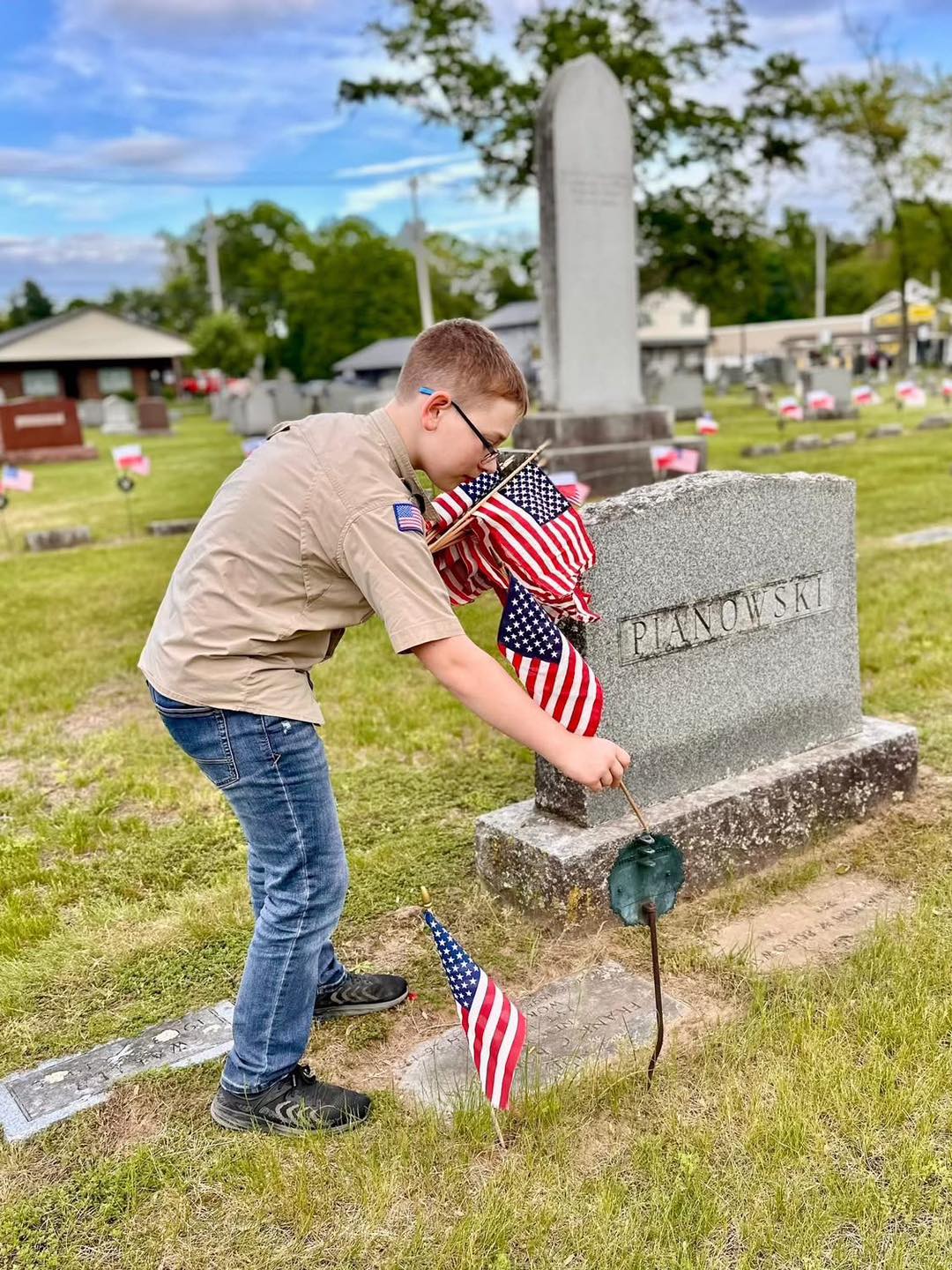 Scout placing American flags at veterans' graves for Memorial Day