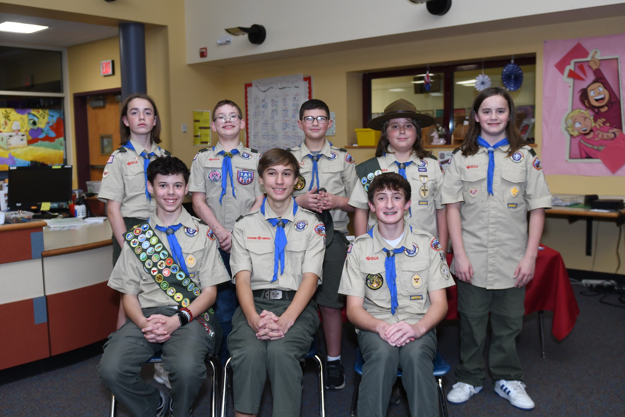 Eight Troop 54 Scouts in full uniform with merit badge sashes and blue neckerchiefs
